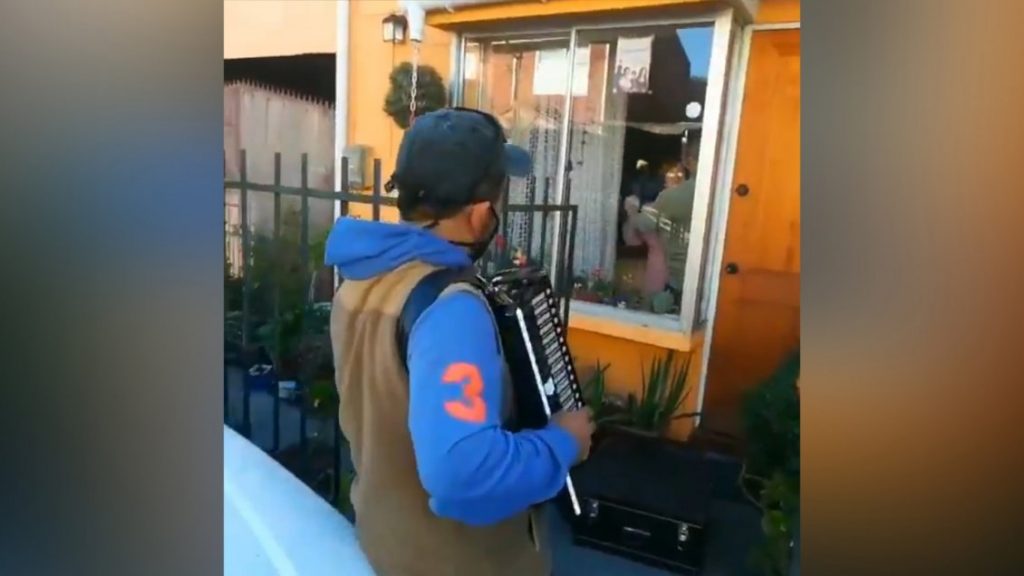 Joven toca acordeón para sus padres enfermos desde fuera de la casa