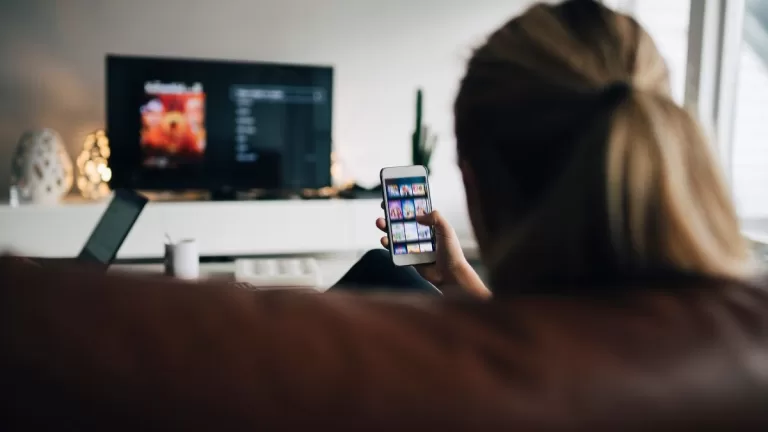 Viendo tele y celular GettyImages-944229620 web