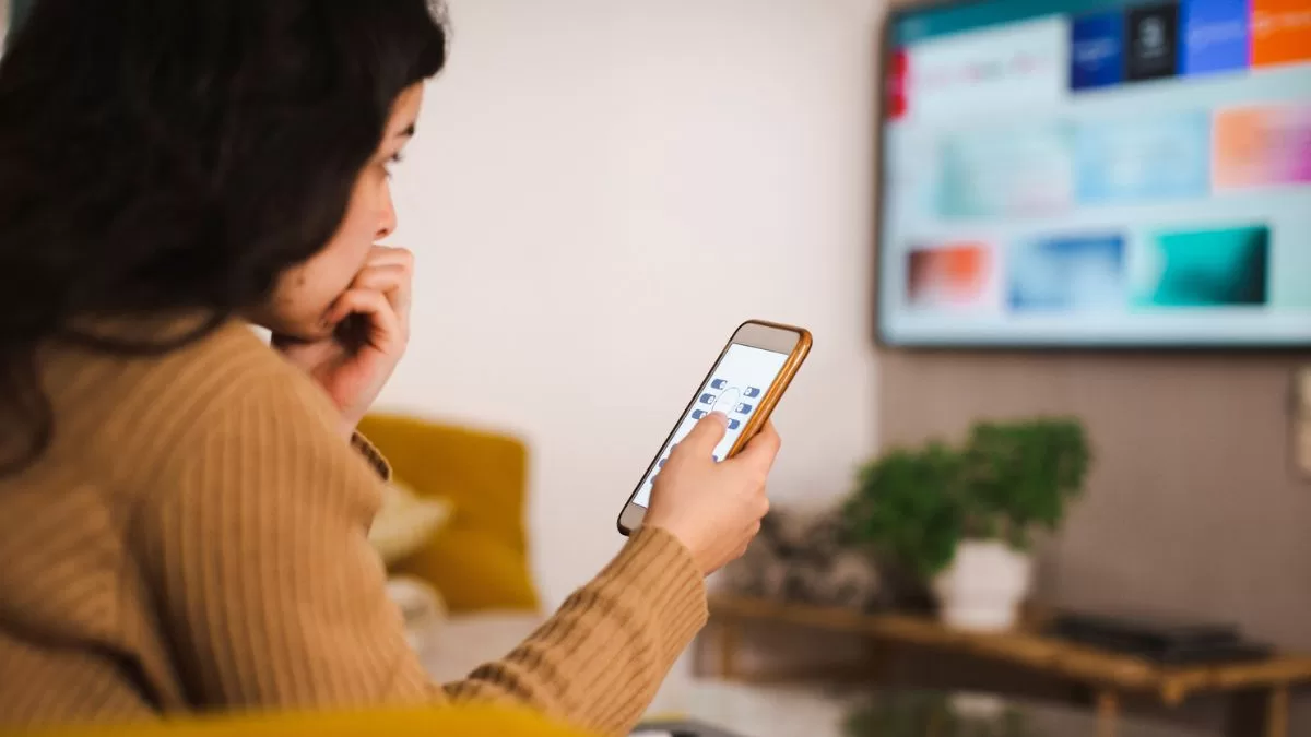 Viendo tele y celular pantalla GettyImages-1400704519 web